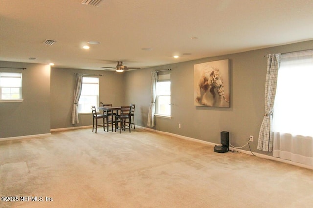 carpeted dining area with ceiling fan and plenty of natural light