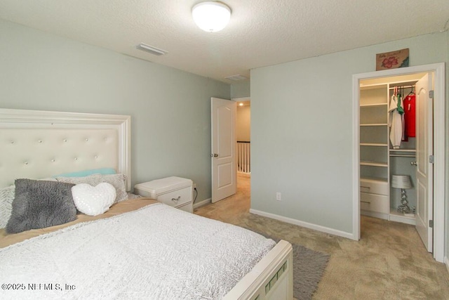 bedroom with light colored carpet, a spacious closet, a closet, and a textured ceiling