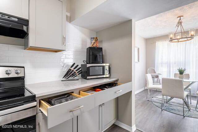 kitchen featuring tasteful backsplash, white cabinets, an inviting chandelier, and stainless steel appliances