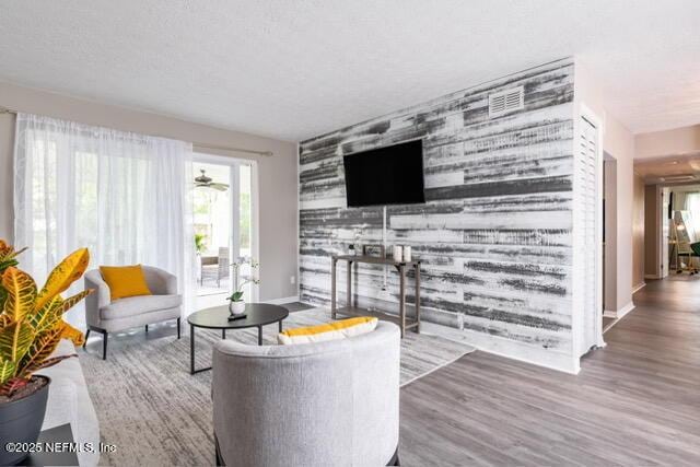 living room featuring ceiling fan, a textured ceiling, and hardwood / wood-style flooring