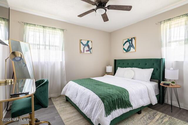 bedroom featuring ceiling fan, multiple windows, and hardwood / wood-style floors