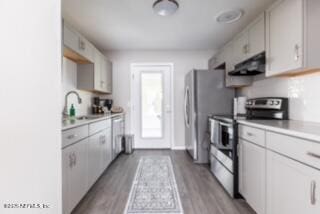 kitchen featuring light hardwood / wood-style floors, sink, white cabinetry, appliances with stainless steel finishes, and ventilation hood