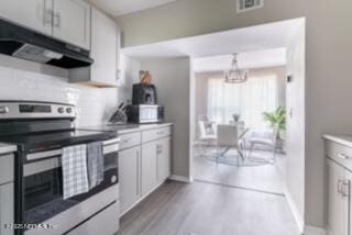 kitchen featuring stainless steel electric range, white cabinetry, and pendant lighting