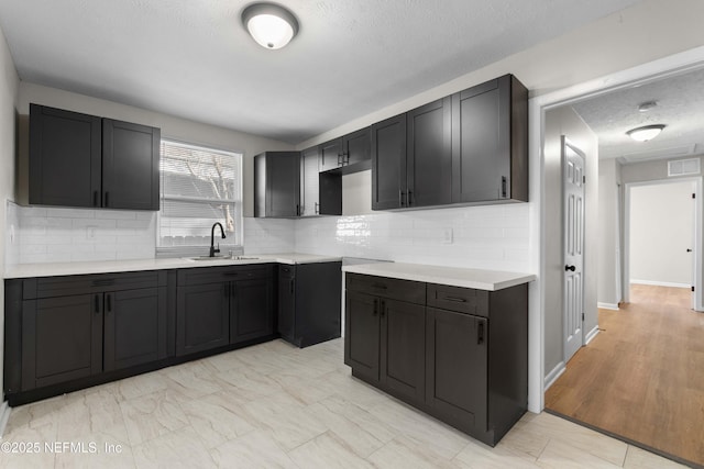 kitchen with tasteful backsplash, sink, and a textured ceiling