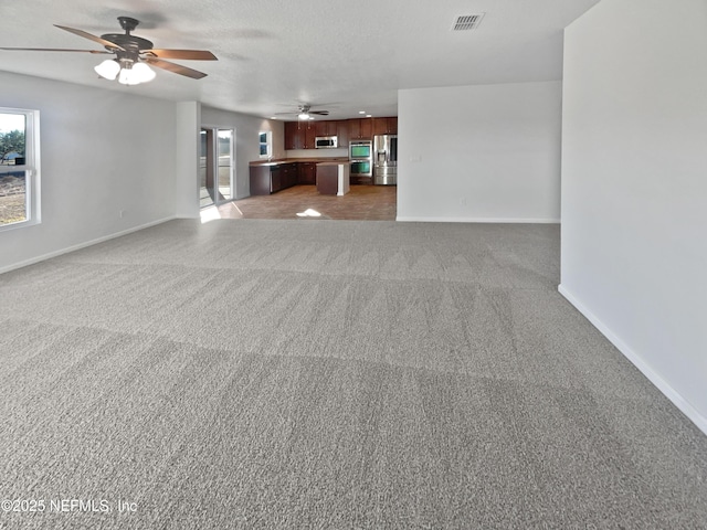 unfurnished living room with ceiling fan, a textured ceiling, and carpet flooring