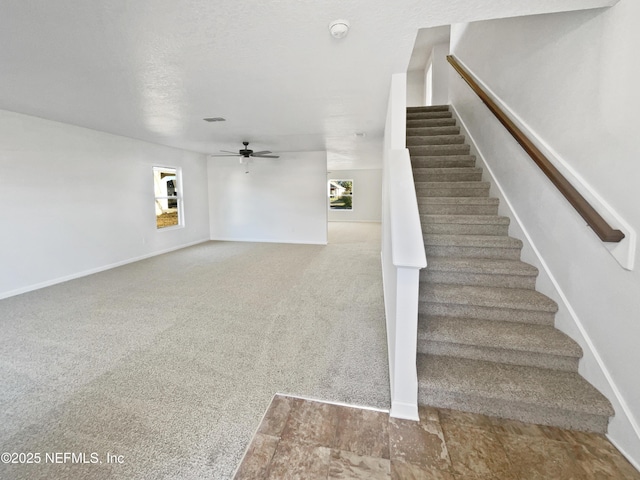 stairs with ceiling fan, a textured ceiling, and carpet floors