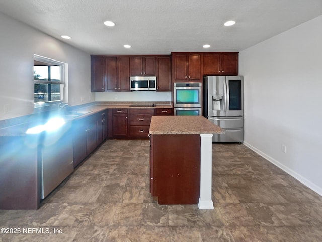 kitchen with kitchen peninsula, sink, stainless steel appliances, and a textured ceiling