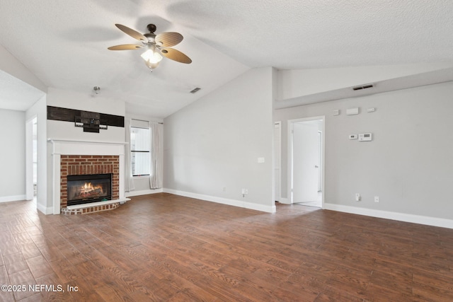 unfurnished living room with lofted ceiling, hardwood / wood-style floors, a textured ceiling, and a brick fireplace