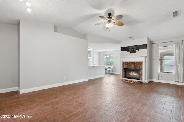 unfurnished living room featuring lofted ceiling, a brick fireplace, dark wood-type flooring, and ceiling fan