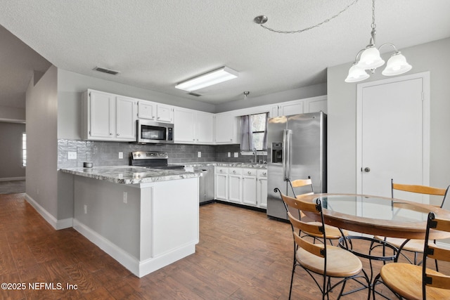 kitchen with white cabinetry, appliances with stainless steel finishes, kitchen peninsula, and decorative backsplash