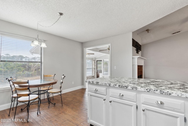 kitchen featuring light stone counters, a textured ceiling, wood-type flooring, and white cabinets