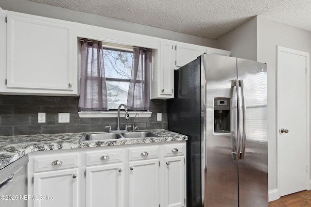 kitchen with sink, white cabinetry, a textured ceiling, appliances with stainless steel finishes, and decorative backsplash