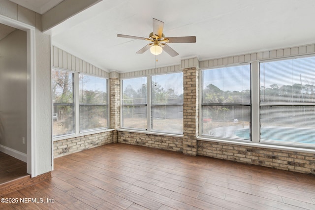 unfurnished sunroom featuring ceiling fan, plenty of natural light, and vaulted ceiling