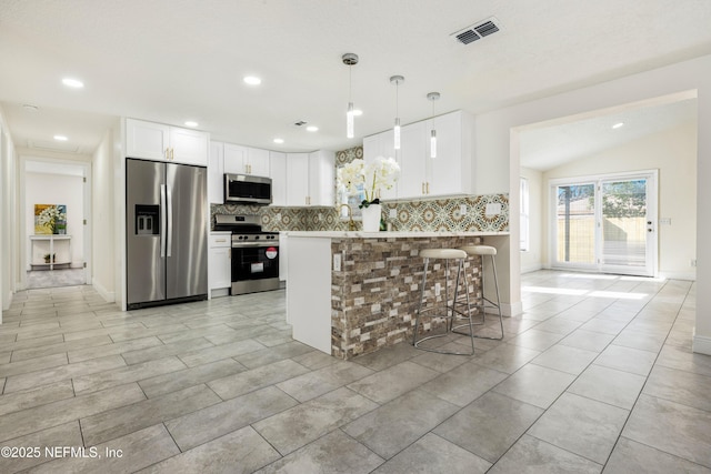 kitchen with pendant lighting, a breakfast bar, kitchen peninsula, white cabinetry, and stainless steel appliances