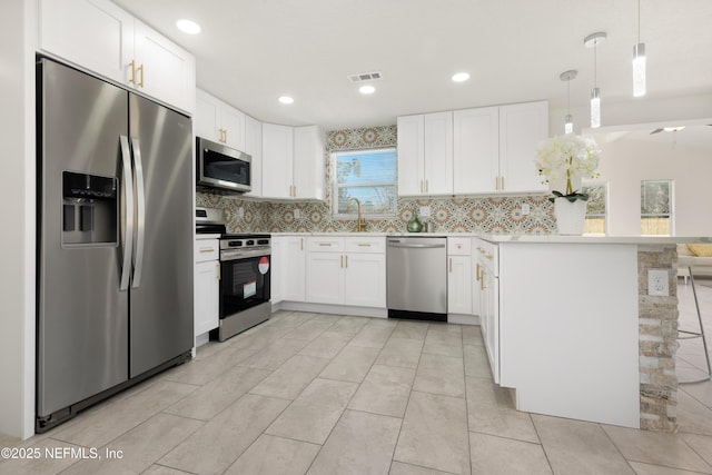 kitchen with tasteful backsplash, kitchen peninsula, hanging light fixtures, stainless steel appliances, and white cabinets