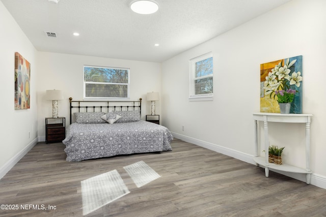 bedroom with a textured ceiling and hardwood / wood-style flooring