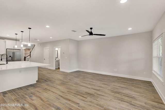 kitchen featuring high end refrigerator, white cabinets, sink, decorative light fixtures, and ceiling fan