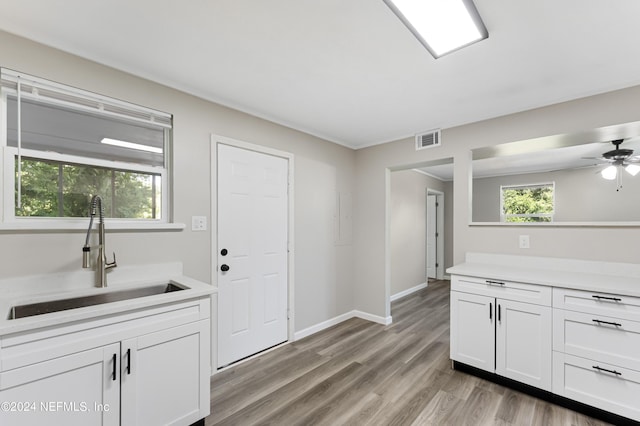 kitchen featuring ceiling fan, sink, white cabinetry, and light wood-type flooring