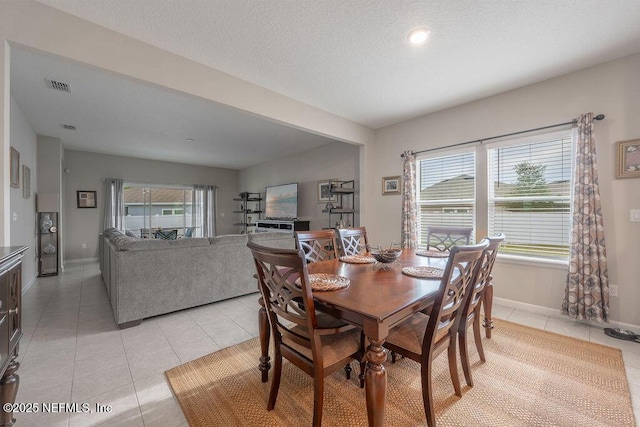 tiled dining room featuring plenty of natural light and a textured ceiling