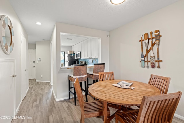 dining room featuring light hardwood / wood-style floors and a textured ceiling