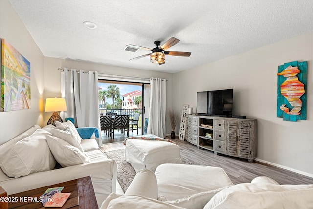 living room with ceiling fan, hardwood / wood-style floors, and a textured ceiling