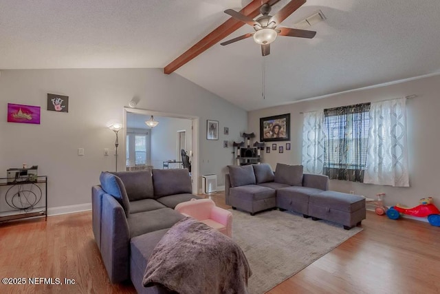 living room with light wood-type flooring, ceiling fan, a textured ceiling, and lofted ceiling with beams