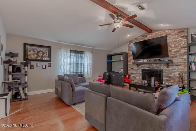 living room featuring light wood-type flooring, a brick fireplace, vaulted ceiling with beams, and ceiling fan