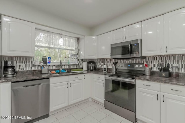 kitchen featuring decorative backsplash, sink, white cabinetry, appliances with stainless steel finishes, and light tile patterned floors