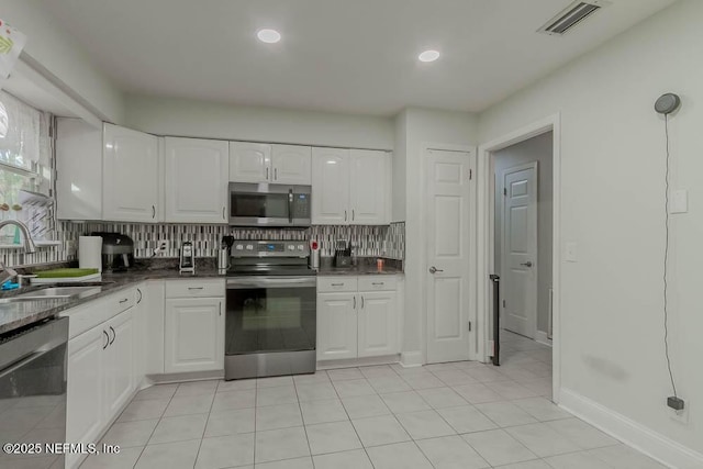 kitchen with tasteful backsplash, sink, light tile patterned flooring, appliances with stainless steel finishes, and white cabinets