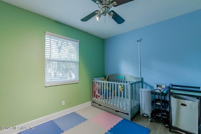 bedroom with ceiling fan and a crib