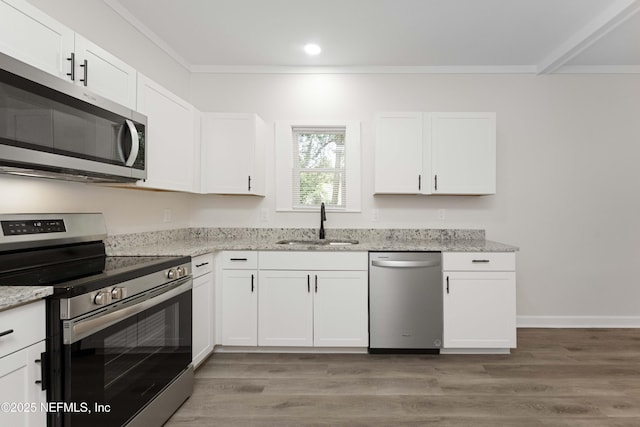 kitchen with stainless steel appliances, white cabinetry, light stone counters, and sink