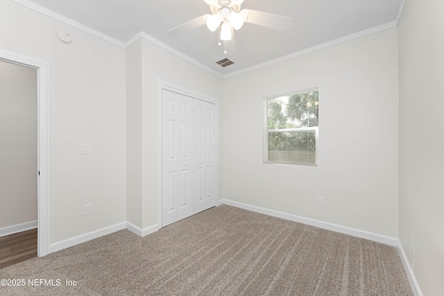 unfurnished bedroom with ceiling fan, carpet, a closet, and crown molding