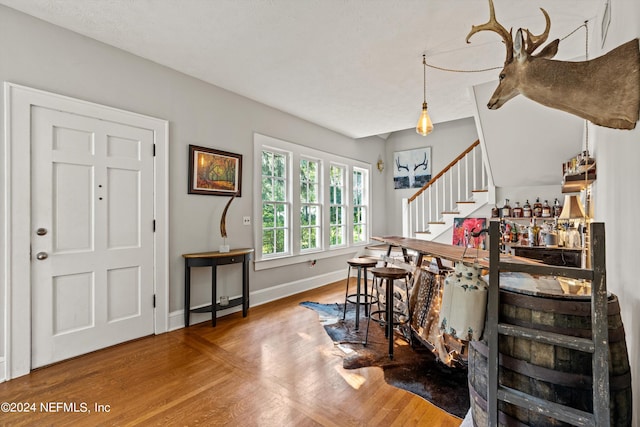 foyer entrance featuring hardwood / wood-style flooring and bar