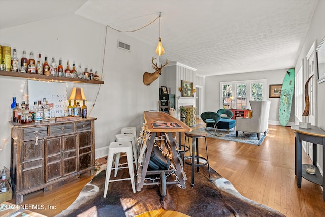 dining room featuring hardwood / wood-style floors, lofted ceiling, and bar