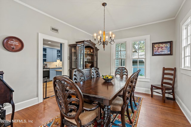 dining room with sink, a chandelier, crown molding, and dark hardwood / wood-style flooring