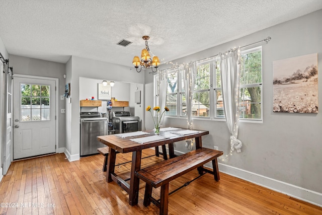 dining room with light wood-type flooring, a textured ceiling, washer and dryer, and an inviting chandelier