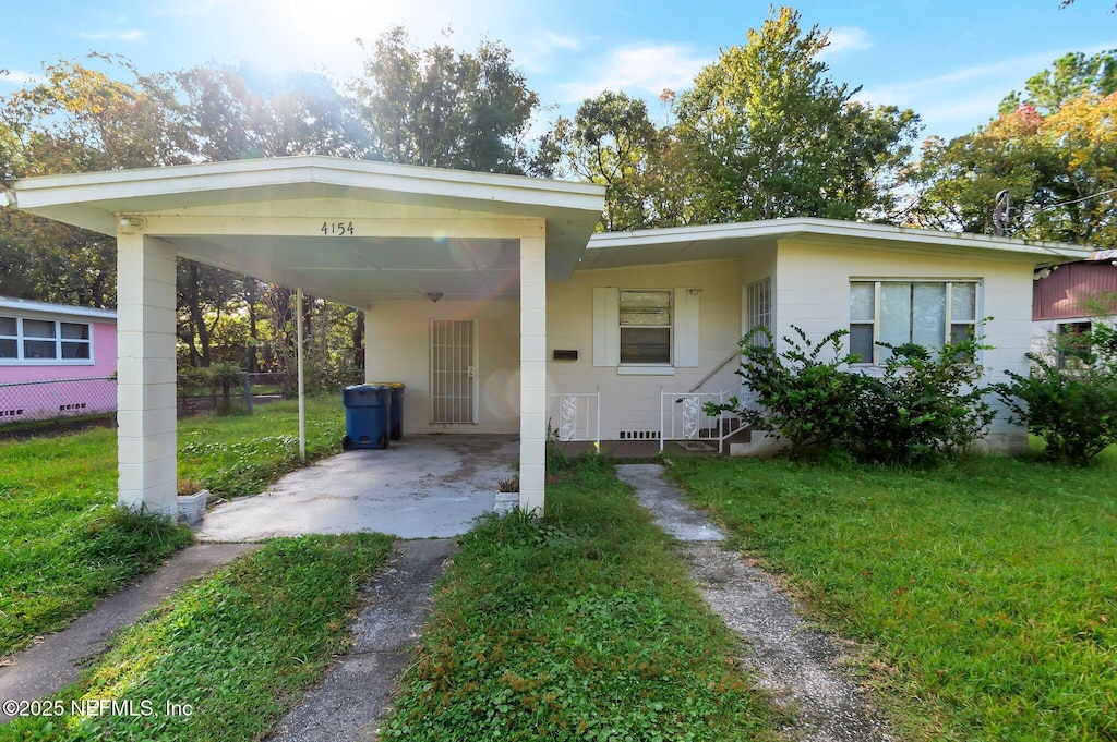 rear view of property featuring a carport and a yard