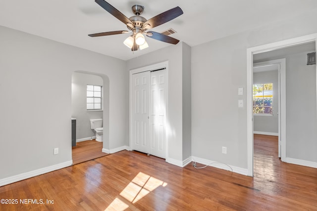 unfurnished bedroom featuring ceiling fan, hardwood / wood-style flooring, and multiple windows