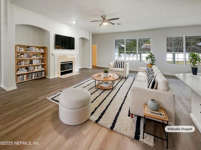 living room with a textured ceiling, ceiling fan, and hardwood / wood-style flooring