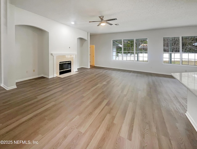 unfurnished living room with a textured ceiling, ceiling fan, and light hardwood / wood-style flooring