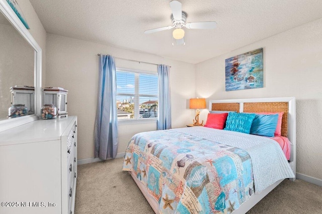 bedroom featuring ceiling fan, a textured ceiling, and light carpet