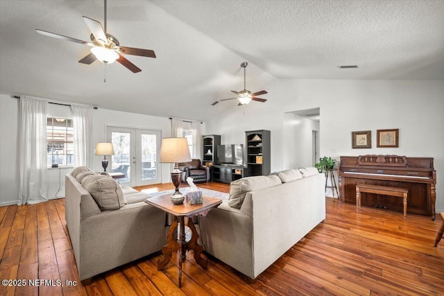 living room featuring a textured ceiling, lofted ceiling, french doors, ceiling fan, and hardwood / wood-style flooring