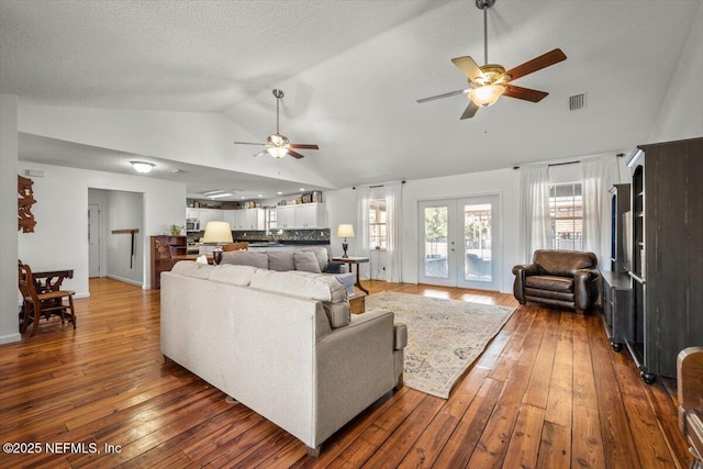 living room with ceiling fan, dark hardwood / wood-style flooring, lofted ceiling, and french doors