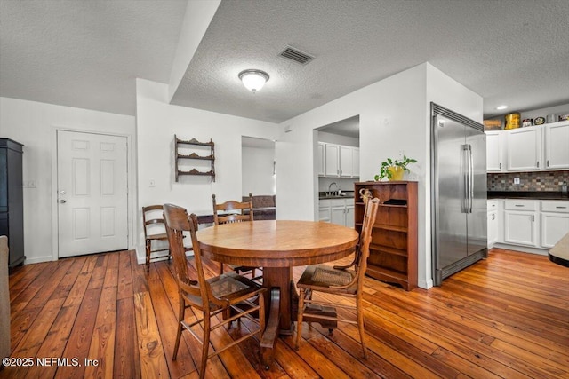 dining space with sink, wood-type flooring, and a textured ceiling