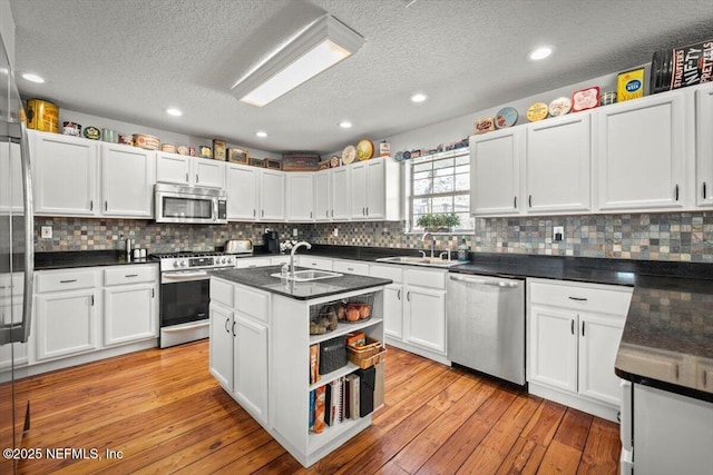 kitchen with a kitchen island with sink, sink, stainless steel appliances, and white cabinetry