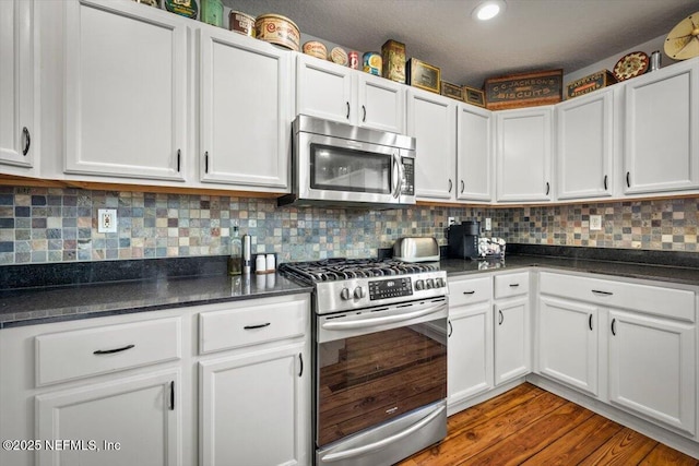 kitchen with tasteful backsplash, hardwood / wood-style flooring, stainless steel appliances, and white cabinetry