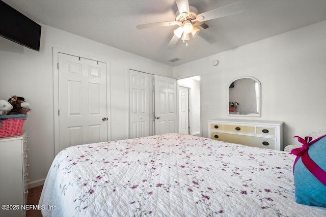 bedroom with ceiling fan and two closets