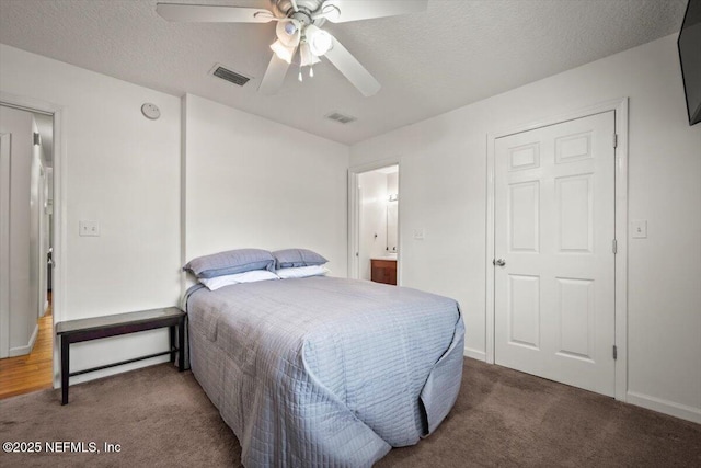 bedroom with ceiling fan, carpet, a textured ceiling, and connected bathroom