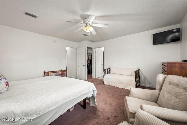 bedroom featuring ceiling fan, dark carpet, a textured ceiling, and a spacious closet