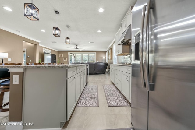 kitchen with stainless steel fridge, a kitchen island, white cabinetry, and pendant lighting